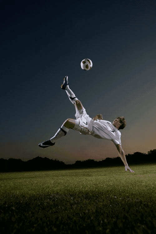 Athlete performing bicycle kick volley against dramatic dusk sky